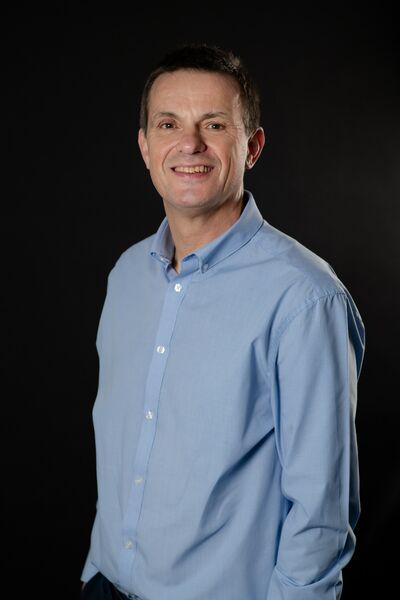 A man in a blue shirt smiles at the camera