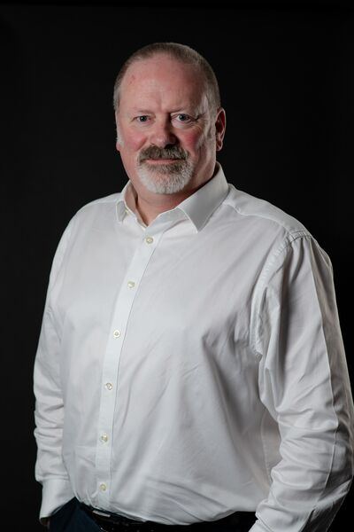 A man in a white shirt looks at the camera