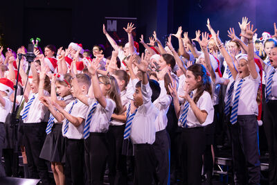 Children singing on stage - with arms raised