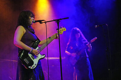 Two girls performing on stage holding guitars