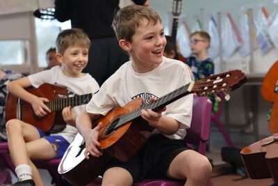 Two young boys playing a guitar