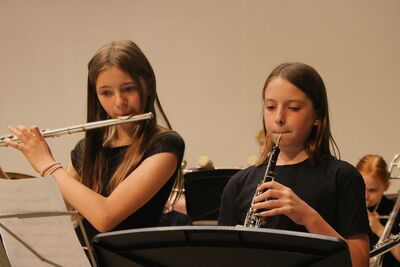 Two girls playing woodwind, one playing flute, the other a clarinet