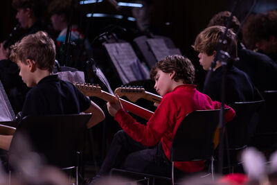 Four boys concentrate learning guitars